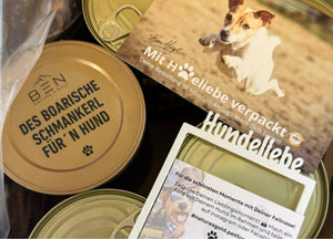 Goldene Dosendeckel mit „Des Boarische Schmankerl für'n Hund“ und Hundeliebe-Polaroidrahmen von Nature's Gold zum internationalen Welthundetag.